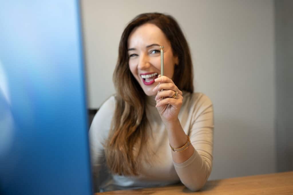Businessfoto einer Mitarbeiterin der lvm Versicherung die lachend mit einem Stift in der Hand in die Kamera schaut